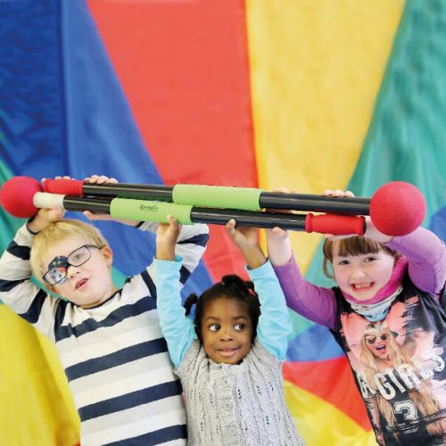 drei lachende Kinder halten Schaumstoffstangen in die Höhe