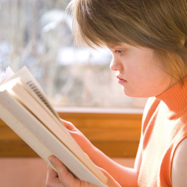 ein Mädchen mit Down-Syndrom beim Lesen