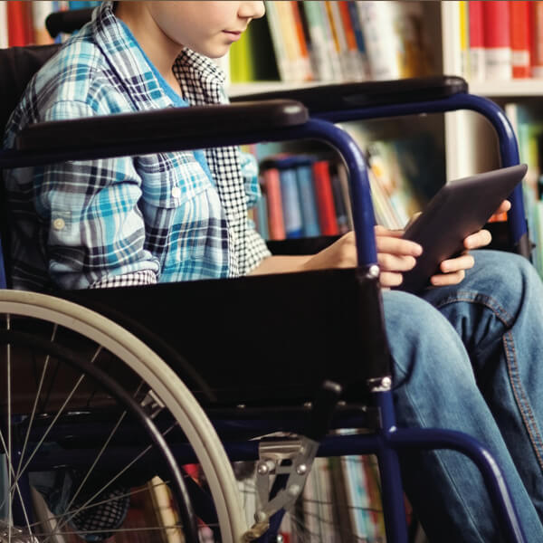 ein im Rollstuhl sitzender Junge in der Bibliothek