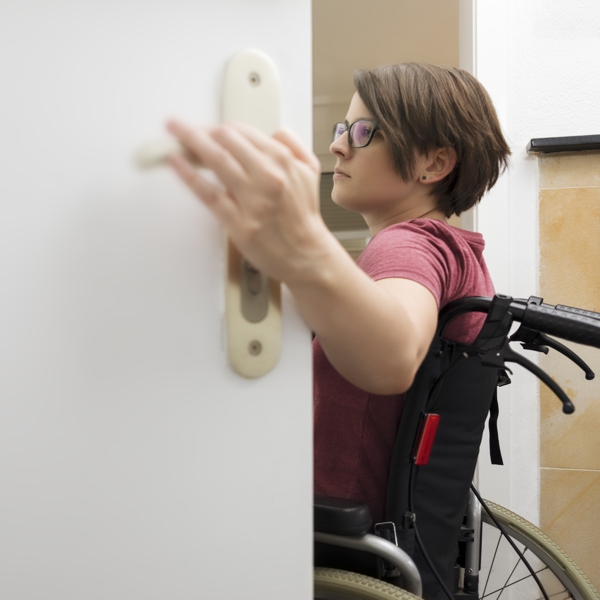Frau im Rolli öffnet Tür
