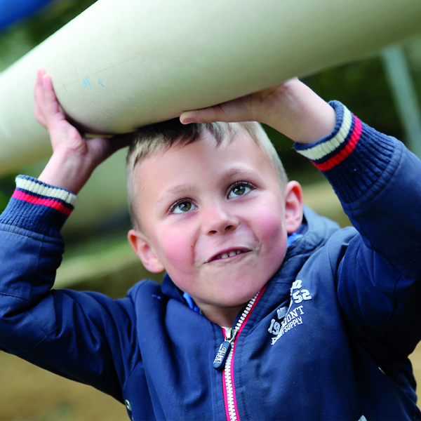 ein kleiner Junge mit konzentriertem Blick auf dem Spielplatz