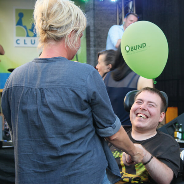 Betreuerin und Teilnehmer im Rollstuhl auf einem Festival