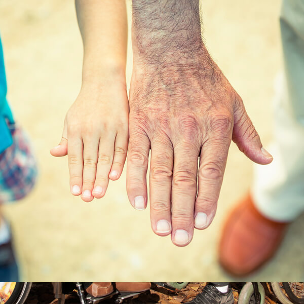 die Hand eines Kindes neben der Hand eines Senioren